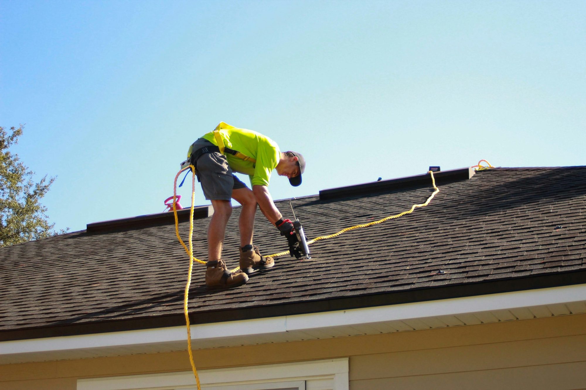 A roofer installing shingles on a residential roof